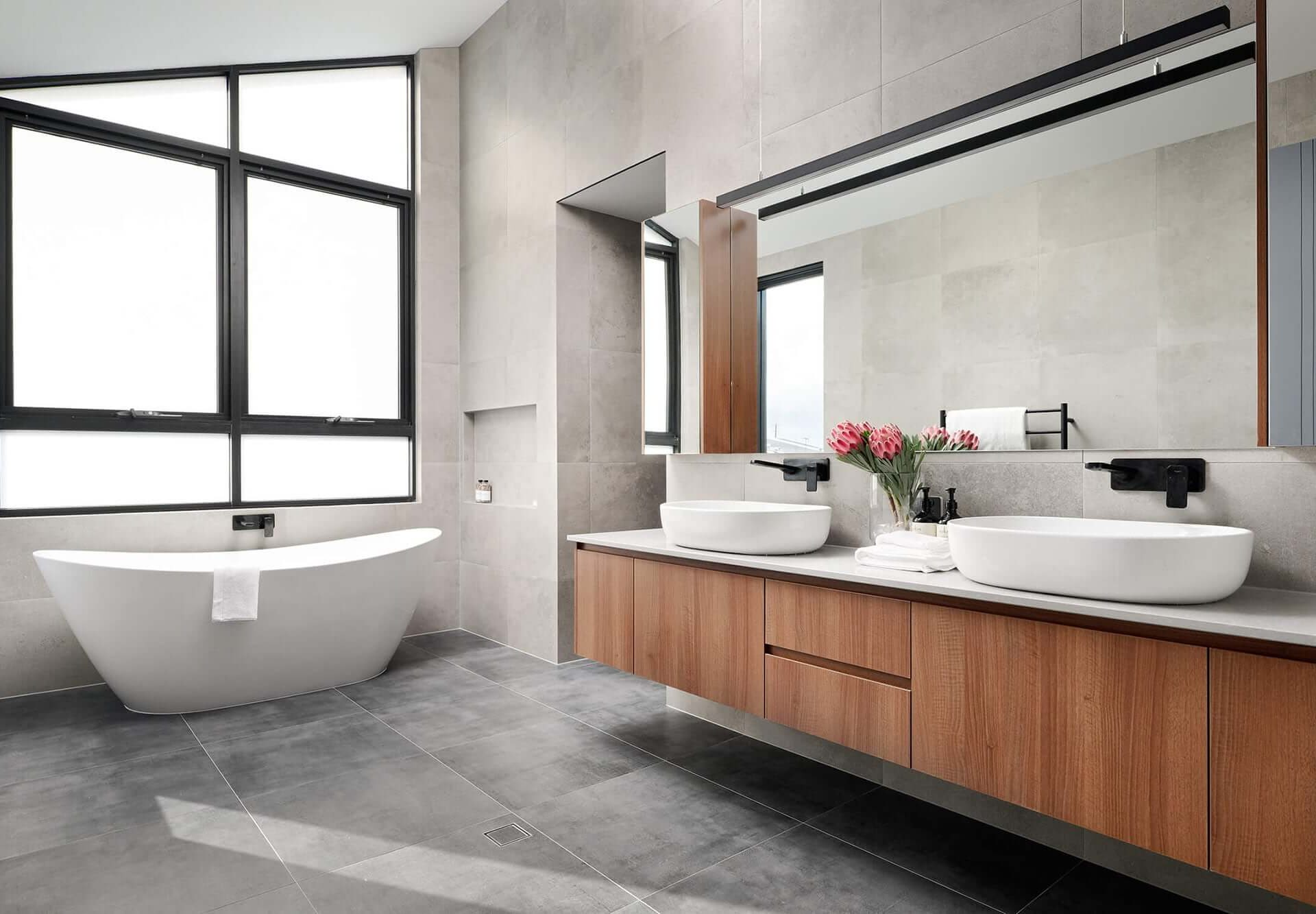 Custom home bathroom featuring a freestanding bath, stone vanity and large windows.