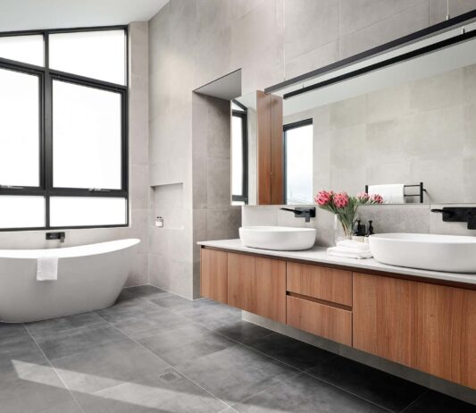 Custom home bathroom featuring a freestanding bath, stone vanity and large windows.