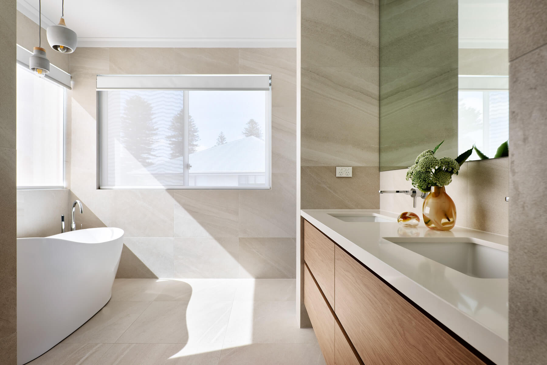 Light-filled bathroom at The Grove in Wembley featuring a stone vanity, large windows and minimalist finishes.