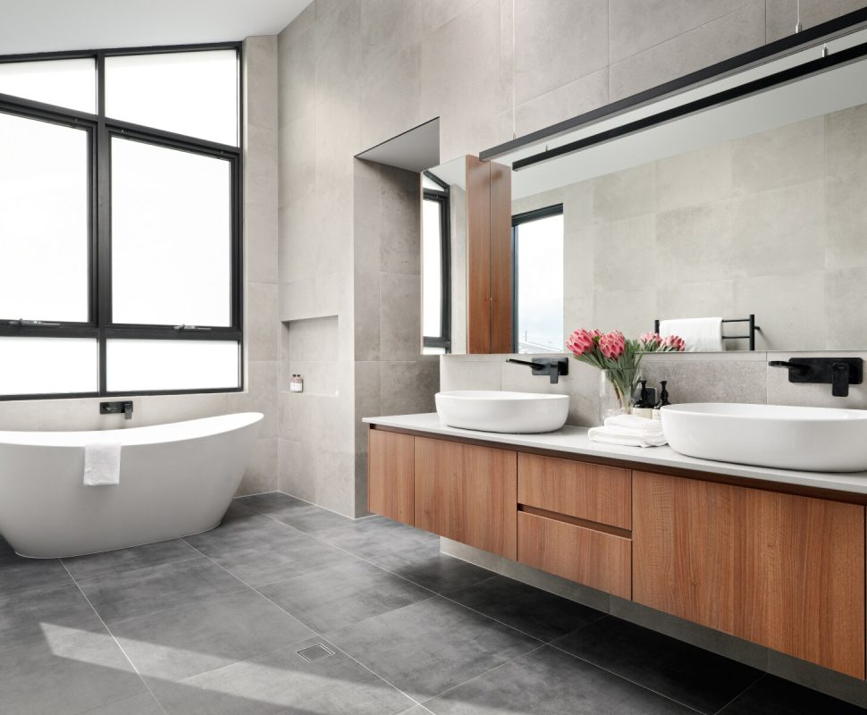 Custom home bathroom featuring a freestanding bath, floating vanity and large windows.