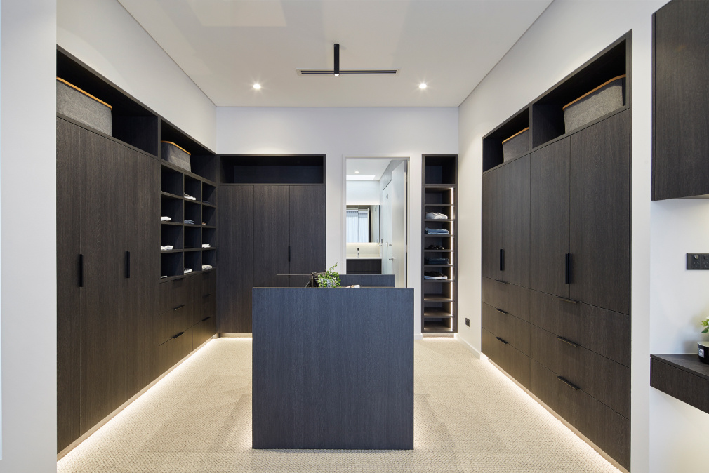 Custom walk-in wardrobe featuring dark timber cabinetry, open shelving and integrated storage.