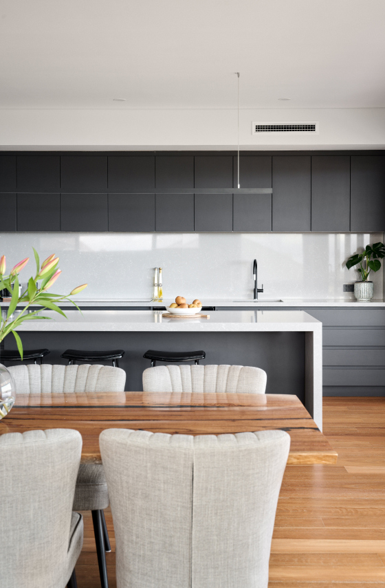 Custom home kitchen featuring timber cabinetry, stone benchtops and integrated appliances.