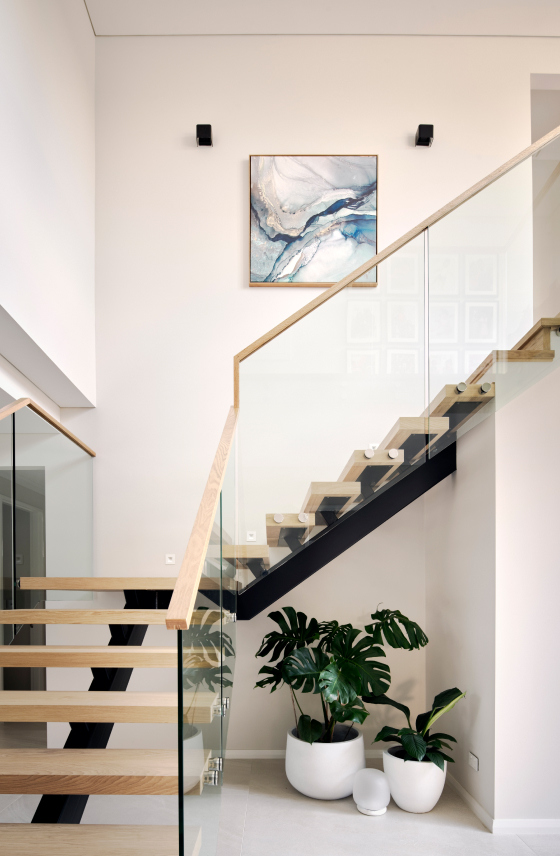 Floating timber staircase with glass balustrading and a timber handrail at The Grove custom home in Wembley.