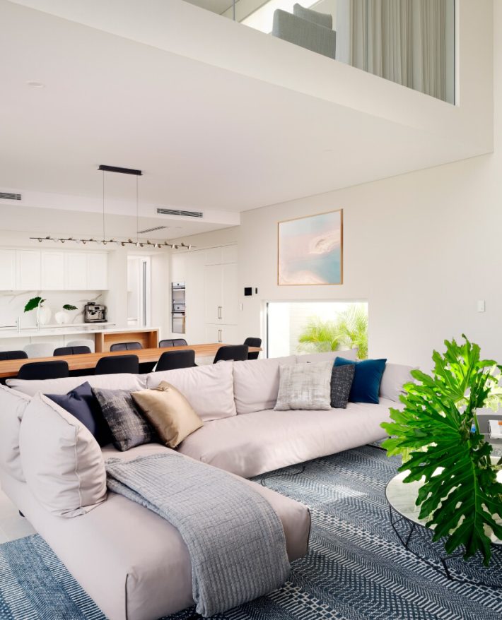 Double-height custom home interior featuring floor-to-ceiling glazing, mezzanine level and open-plan living.