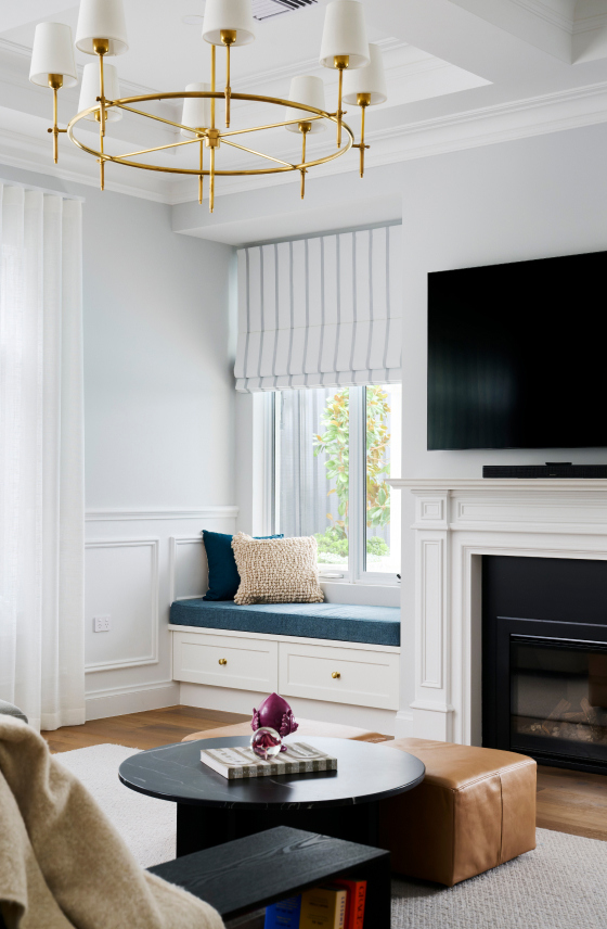 Custom home living room on Lombardy Street featuring decorative wall panelling, a built-in fireplace and pendant lighting.