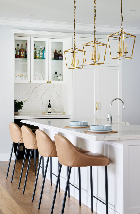 Custom home kitchen on Lombardy Street featuring white cabinetry, stone island benchtop, timber stools and brass pendant lighting.
