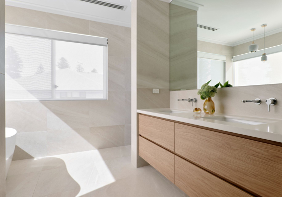 Custom home bathroom at The Grove in Wembley featuring a stone vanity, large windows and minimalist finishes.