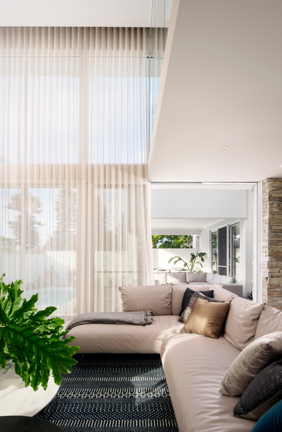 Light-filled lounge area at The Grove in Wembley featuring floor-to-ceiling curtains, large windows and a double-height ceiling.