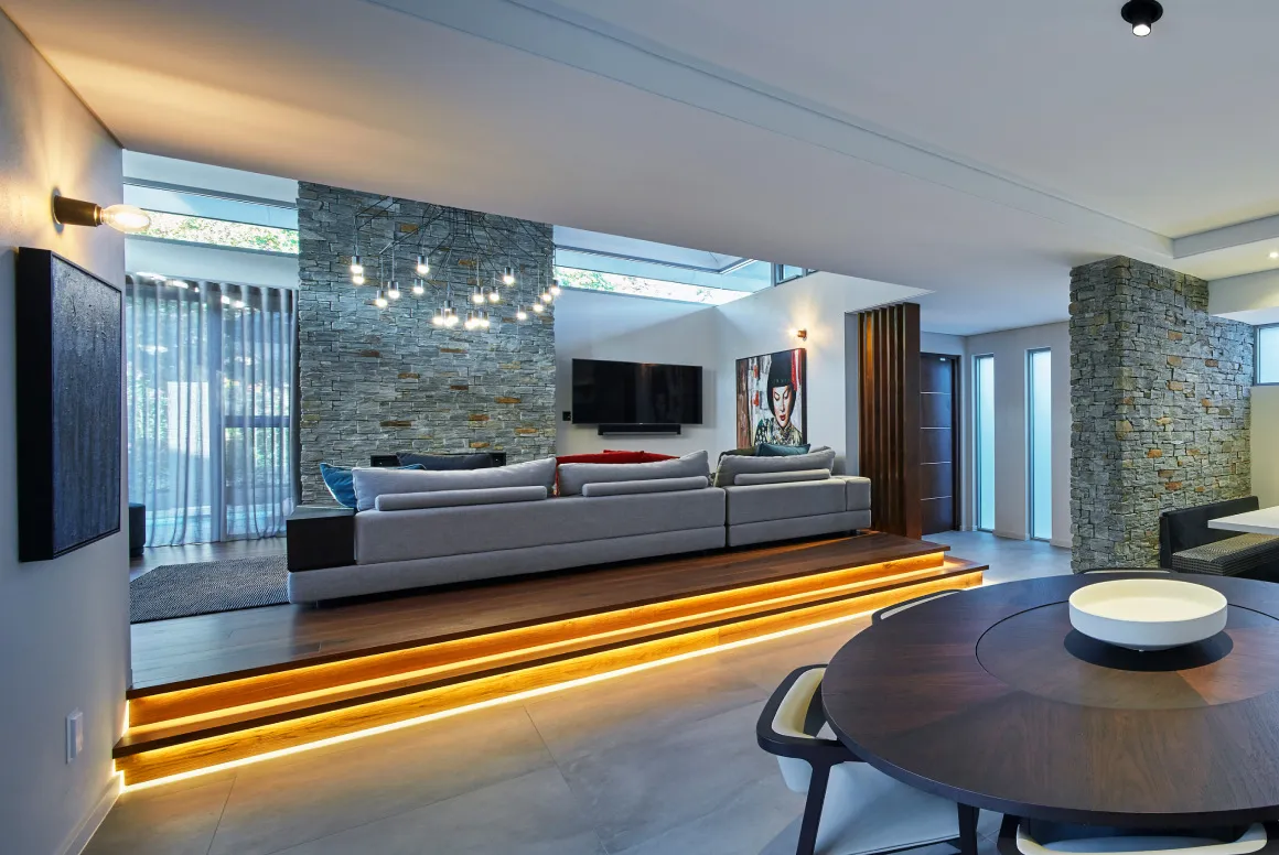 Open-plan living area featuring stone feature walls, expansive glazing and contemporary furnishings.