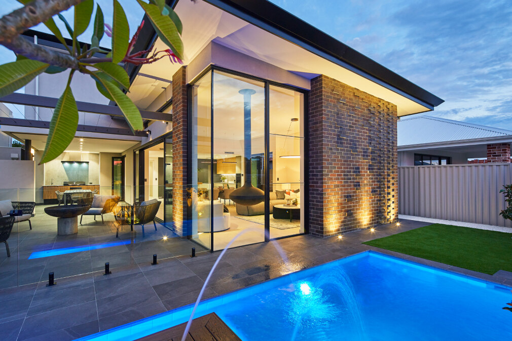 Redmond Street custom home featuring a swimming pool, outdoor entertaining area and expansive glazing at dusk.