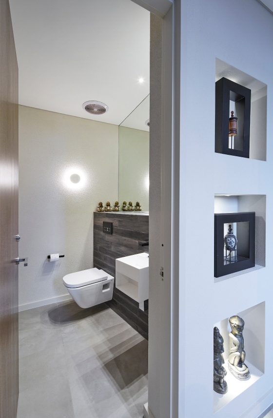 Bathroom featuring recessed display shelving, stone finishes and soft architectural lighting.