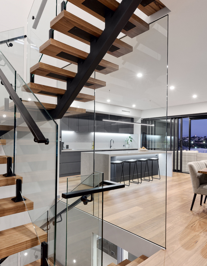 Three-storey custom home interior featuring a floating timber staircase, glass balustrading and expansive glazing.