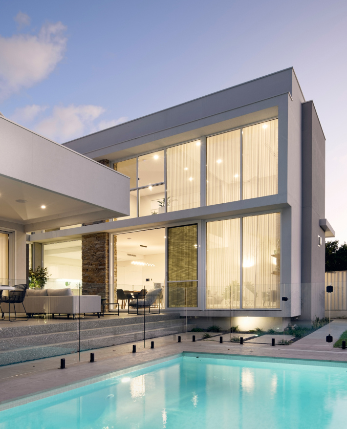 Contemporary custom home in Wembley featuring double-height glazing, angular rooflines and a swimming pool.