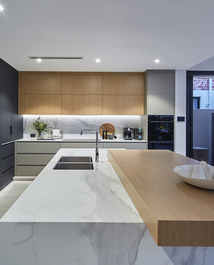 Contemporary custom home kitchen featuring timber cabinetry, stone benchtops and a minimalist design.