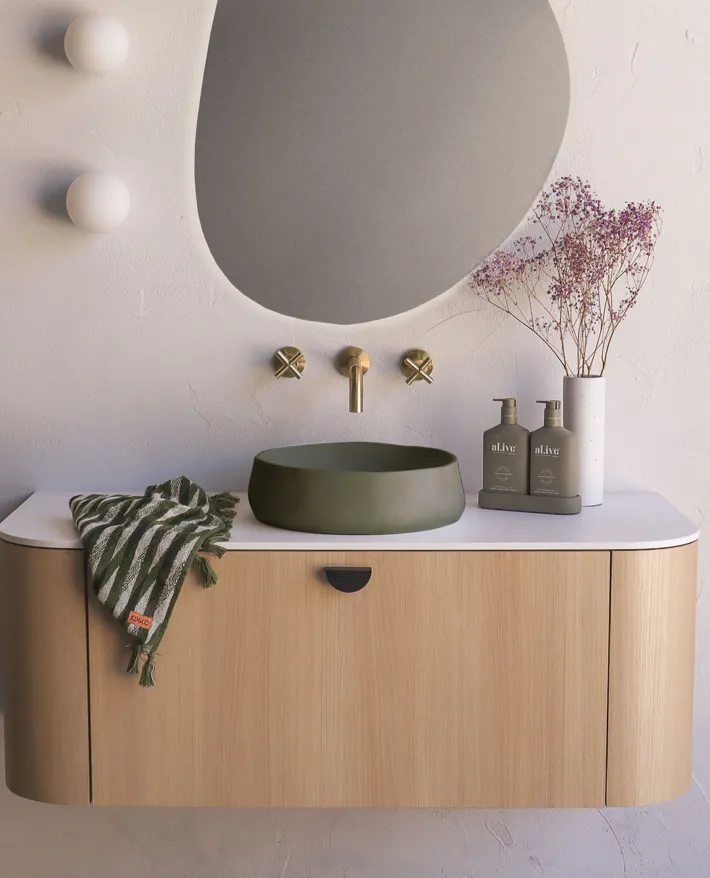 Decorative bathroom basin with a round mirror, stone-look vanity and contemporary accessories.