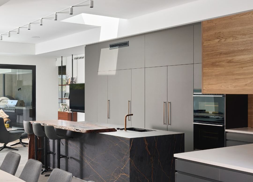 Modern custom home kitchen featuring dark cabinetry, stone island benchtop and open-plan layout.