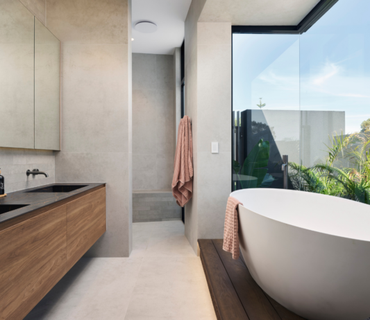 Luxury bathroom in a Marmion custom home featuring a freestanding bath, natural stone finishes and large windows.