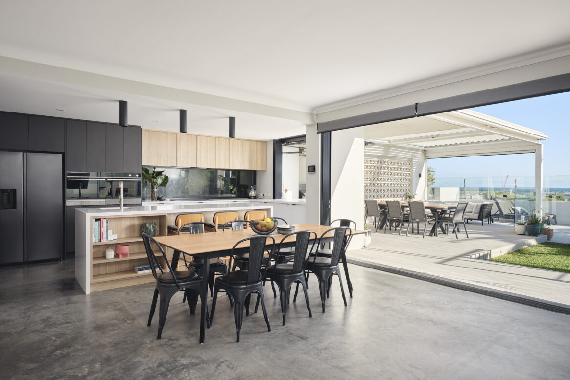 Contemporary open-plan kitchen and dining area featuring large windows, modern cabinetry and ocean views.