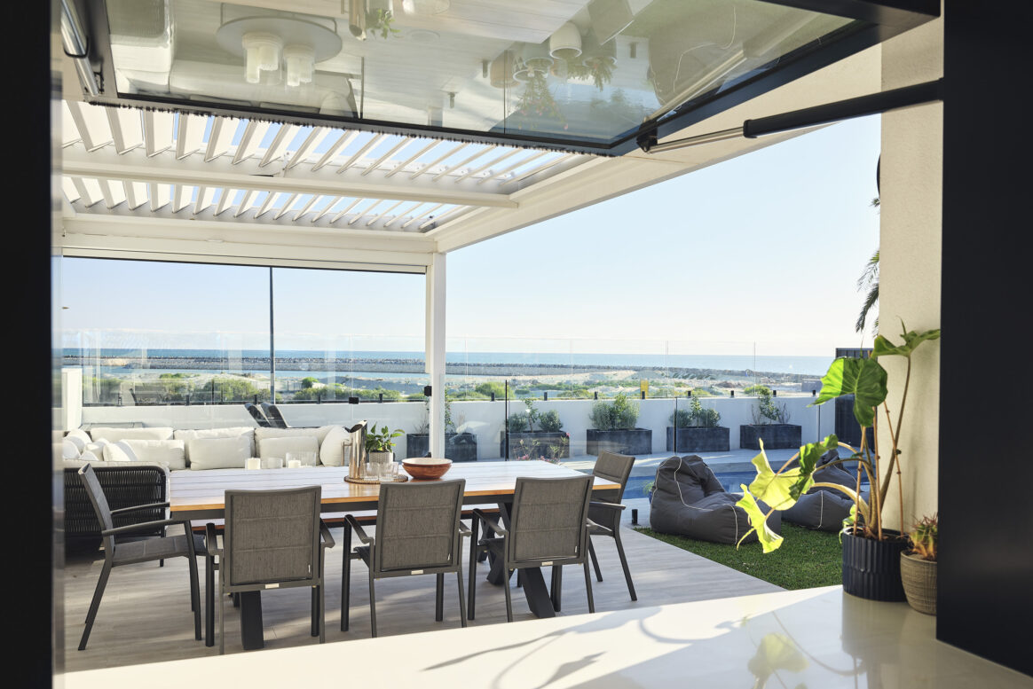 Covered alfresco dining area featuring outdoor furniture, overhead glazing and uninterrupted ocean views.