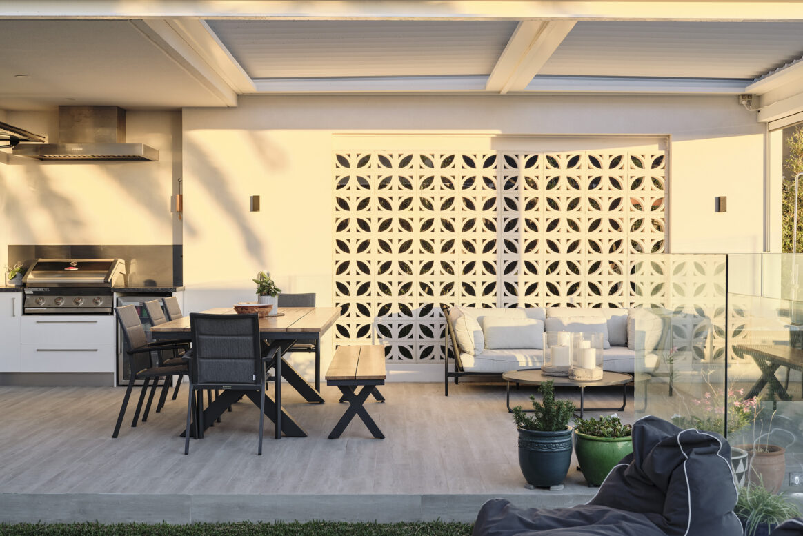 Covered alfresco entertaining area featuring outdoor dining furniture, decorative breeze-block screening and timber ceiling detailing.