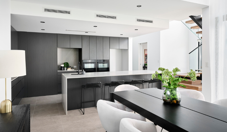 Modern kitchen in an Ardross custom home featuring dark cabinetry, stone island benchtop and open-plan living.