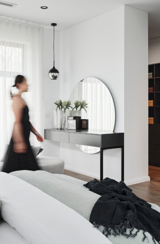 Contemporary master bedroom in an Ardross custom home featuring a curved mirror, timber cabinetry and decorative lighting.