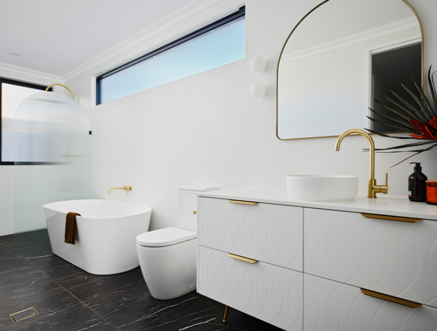 Grosvenor custom home bathroom featuring a freestanding bath, stone finishes, brass tapware and natural light.