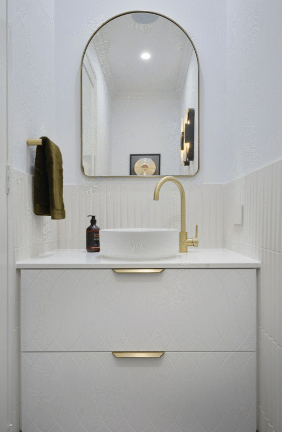 Contemporary powder room featuring a marble-look basin, brass tapware and decorative wall detailing.