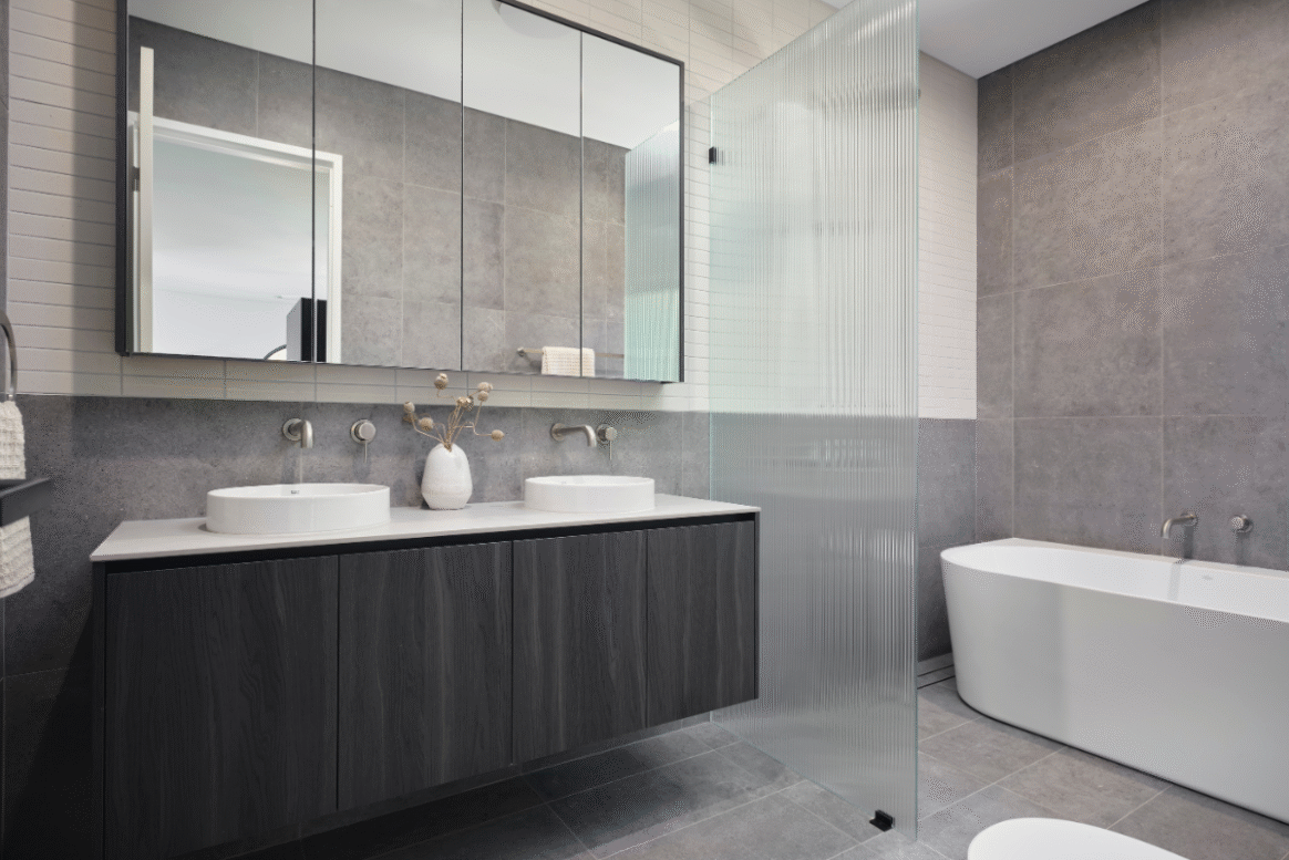 Contemporary bathroom in a Nedlands custom home featuring a freestanding bath, dark stone vanity and large windows.