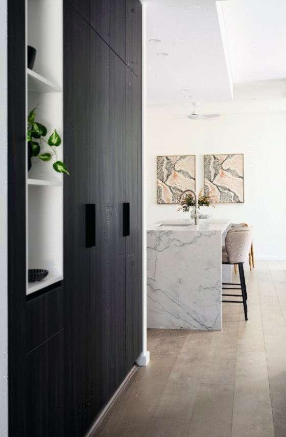Light-filled entry hallway in a Nedlands custom home featuring white cabinetry, decorative artwork and timber flooring.