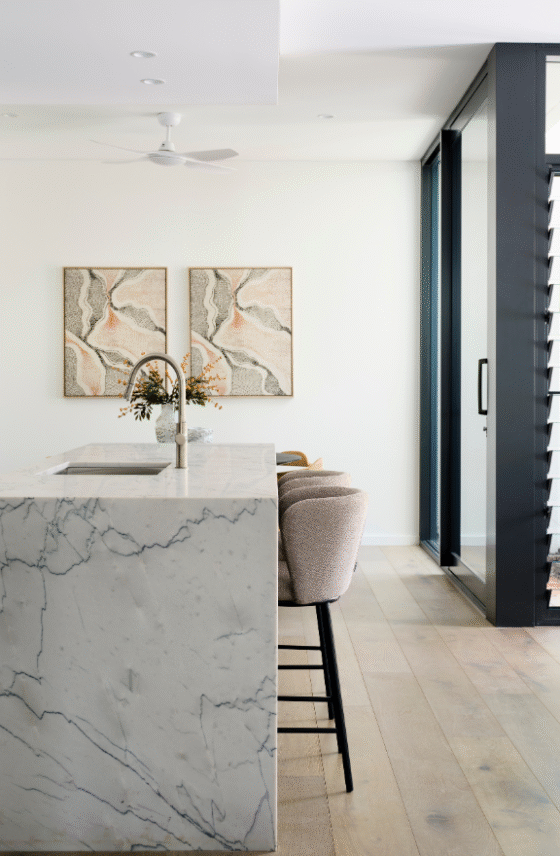Contemporary kitchen island with stone benchtop, decorative artwork and white cabinetry in a Nedlands custom home.