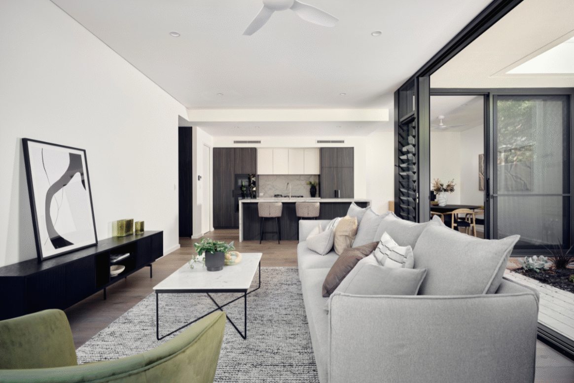 Open-plan living and kitchen area in a Nedlands custom home featuring white cabinetry, timber flooring and contemporary furnishings.