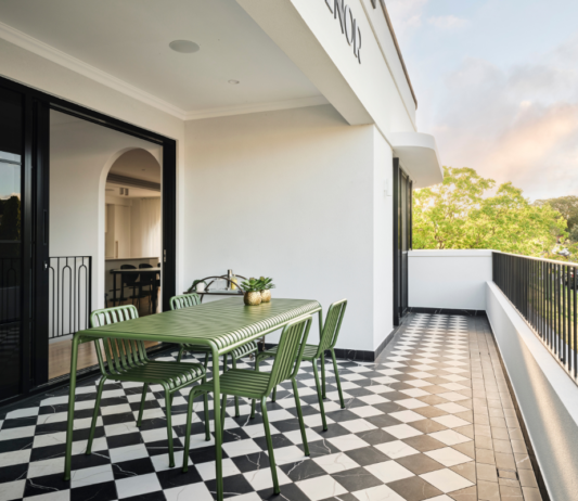 Outdoor balcony with dining furniture, glass balustrading and leafy views at a Art-Deco custom home in Mount Lawley, Perth.