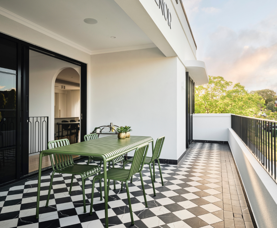 Outdoor balcony with dining furniture, glass balustrading and leafy views at a Art-Deco custom home in Mount Lawley, Perth.