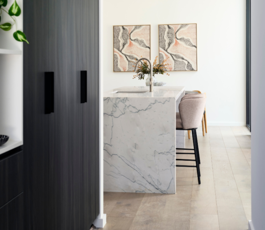 Custom home kitchen in Nedlands featuring a marble-look splashback, white cabinetry and decorative artwork.