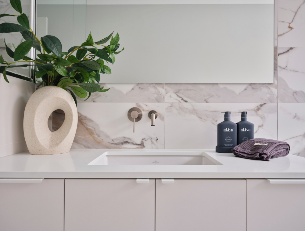 Marble-look bathroom splashback with decorative accessories and greenery in a Mount Lawley home.