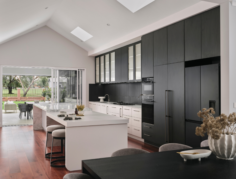 Open-plan kitchen with dark cabinetry and large windows overlooking the outdoor living area in Mount Lawley.