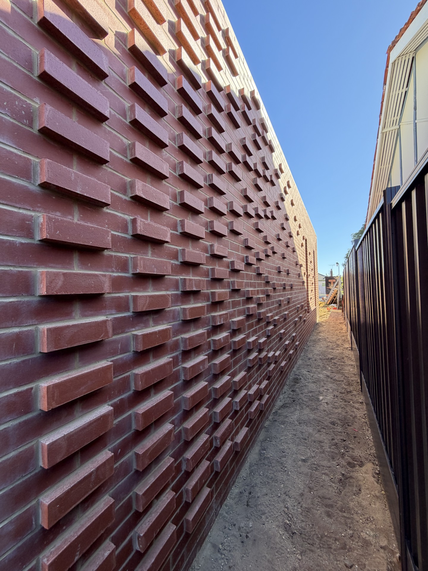 Feature red brick wall with protruding brickwork detailing at a custom home under construction in Floreat, Perth.